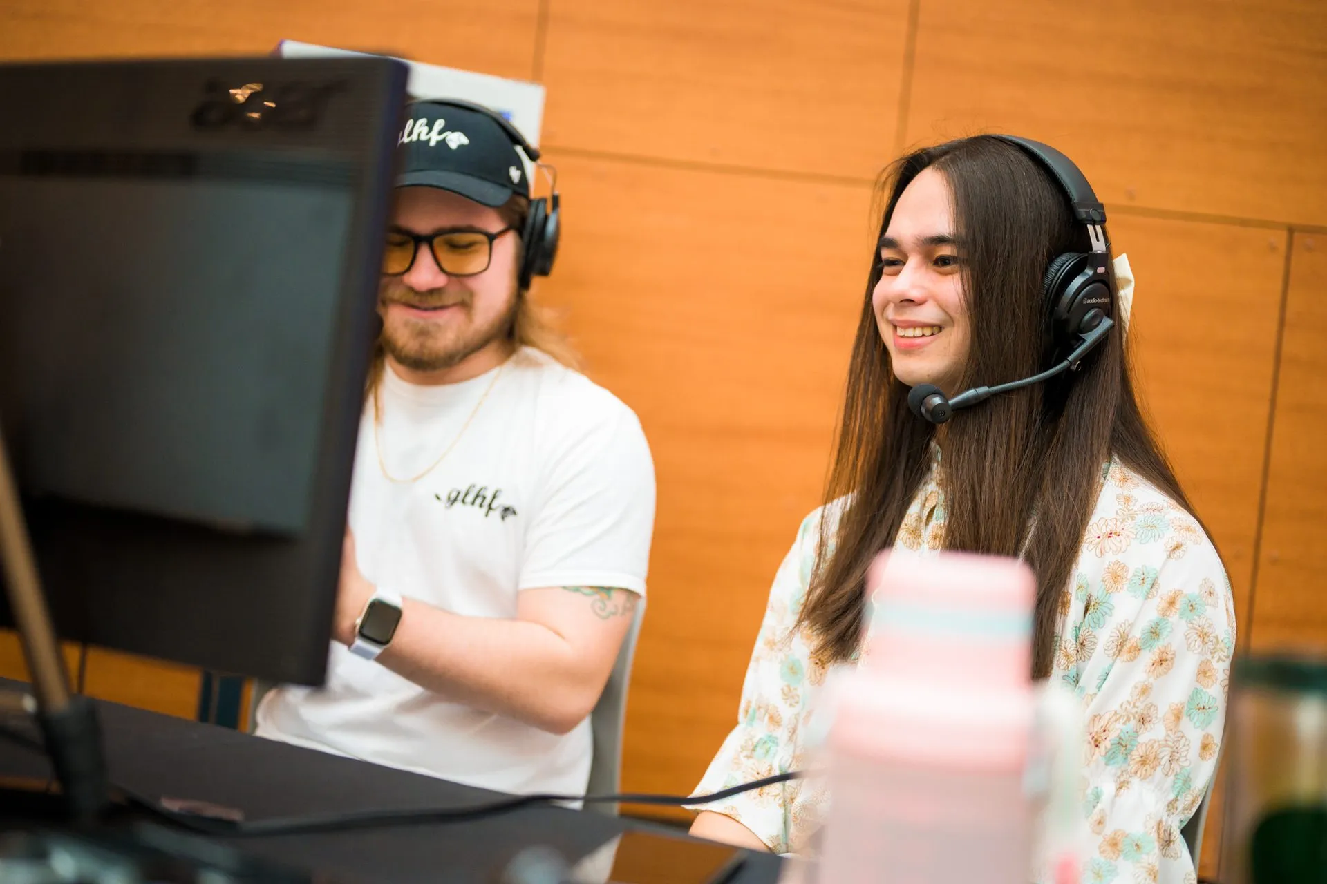 Two players in headsets compete side by side at a tournament station