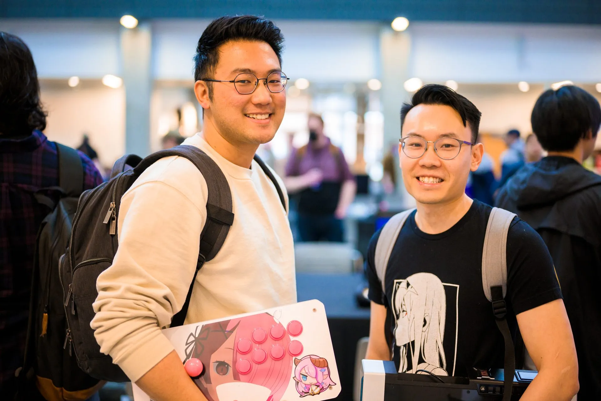 Two friends smiling, one holding a Nintendo Switch, at a gaming event